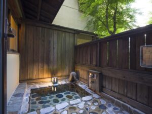 Bagno esterno privato in pietra, circondato da una recinzione in legno