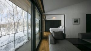 Verschneite Bäume, gesehen durch große Zimmerfenster